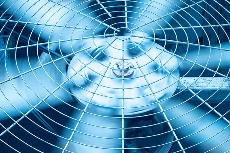 Up close of air conditioning unit fan blades spinning.