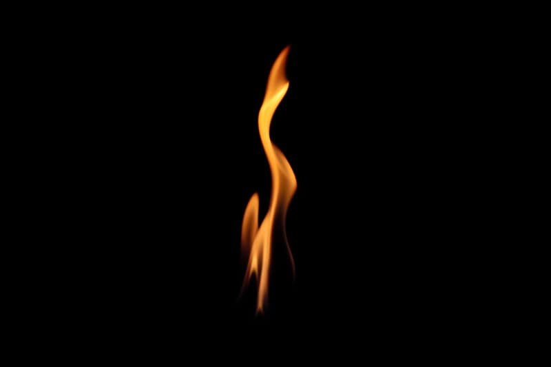 One single orange flame with a black background.