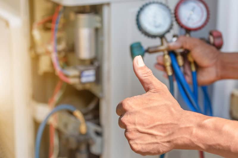 Close up of HVAV repairman on the floor fixing air conditioning system.