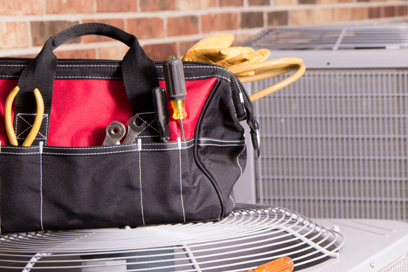 HVAC technicians tool bag sitting on top of an air conditioning unit.
